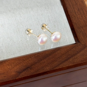 Detailed macro view of high-quality pearl stud earrings with golden butterfly backings