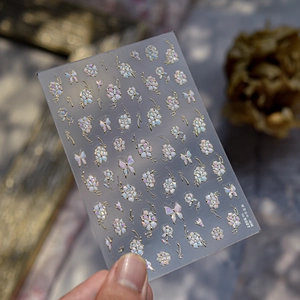 Detail of peony and butterfly nail stickers with gold outlines and iridescent shell texture
