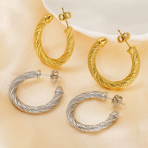 Detail of twisted rope C-hoop earrings in gold and silver finish on silk fabric