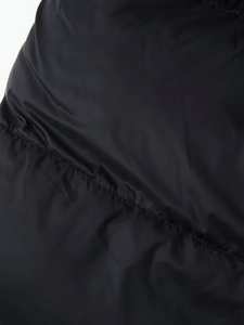 Detailed close-up of black quilted puffer jacket fabric showing smooth shiny texture