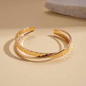Detail of gold double-layered cuff bracelet featuring hand-hammered and mirror finishes