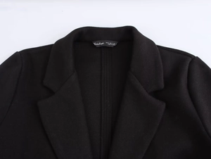 Detail of notch lapel and neck label on a premium black blazer jacket for women
