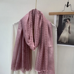 Detail of pink linen lace scarf draped on a white sweater showing delicate texture