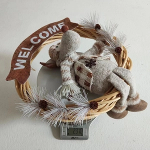 Detail of Christmas wreath with plush reindeer and wooden Welcome sign hanging decor