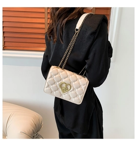 Detailed back view of a beige quilted crossbody bag with heart clasp and chain strap