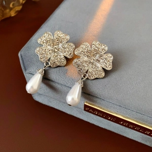 Macro view of crystal flower earrings with dangling drop pearls on a gray jewelry box