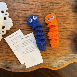 Handmade crochet worry worms in blue and orange yarn with supportive poem cards
