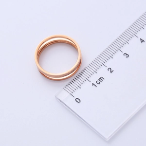 Top view of a three-layer rose gold titanium steel ring measured with a metric ruler