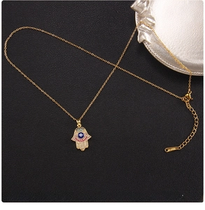 Macro shot of 45cm gold Hamsa Hand pendant with blue Evil Eye and colorful zircon stones