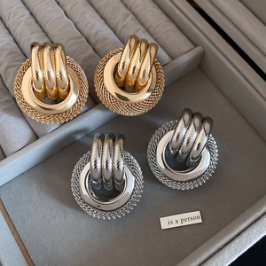 Détail de boucles d'oreilles torsadées dorées et argentées sur velours gris
