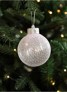 Macro detail of pink lace mesh Christmas ball ornament hanging on a festive tree branch