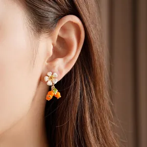 Vintage flower and orange berry dangle earrings with gold accents on model