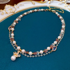 Detail of double-layer necklace with pearl, red stones and crystal bow pendant