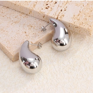 Macro view of silver waterdrop stud earrings with polished mirror finish on stone stand