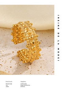 Close-up of golden irregular beaded texture ring on beige stone background