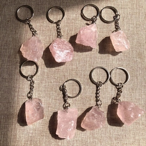 Detailed view of eight irregular pink crystal raw stones on silver metal keychains