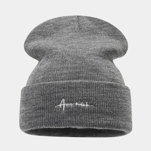 Detailed close-up of dark grey knitted beanie with white cursive embroidery on cuff