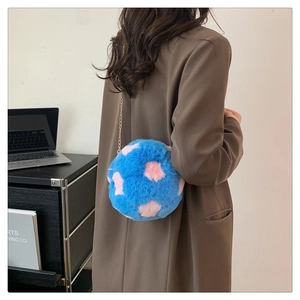 Blue plush sphere crossbody bag with pink dots and gold chain strap shown on model