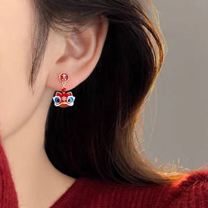 Detailed view of red lion head earrings with lucky character design on model ear
