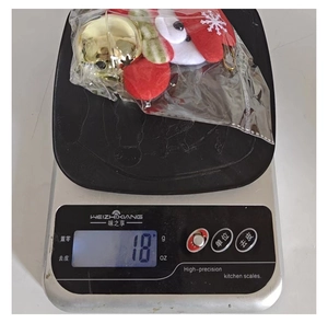 Detail showing a Christmas plush ornament with golden bell weighing 18g on a scale