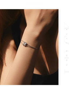 Detail of silver double-layer bracelet with sparkling clover and heart-shaped pendants