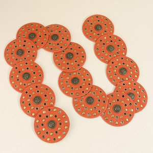 Detailed close-up of orange leather patches with bronze studs on a vintage belt