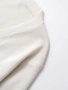 Detailed view of the fine rib-knit texture and soft fabric on a white V-neck cardigan