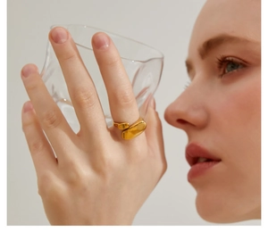 Close-up of an irregular geometric oval open ring in 18k gold finish on a hand
