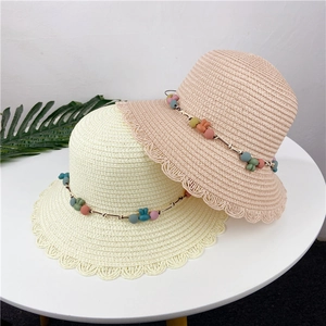 Close-up of woven straw hats featuring scalloped edges and cute rainbow rabbit beads