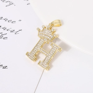 Macro detail of crown letter H pendant with pavé cubic zirconia and gold plating