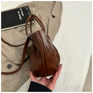 Detail of vintage dark brown pleated bag with round handle and soft leather texture