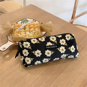 Detail of floral corduroy pencil case with black zipper and merciparis label on wood