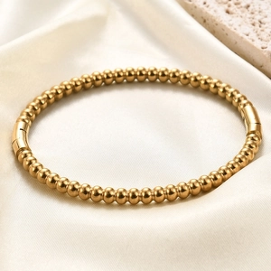 Minimalist 5mm gold beaded stainless steel bangle on white silk with textured rock