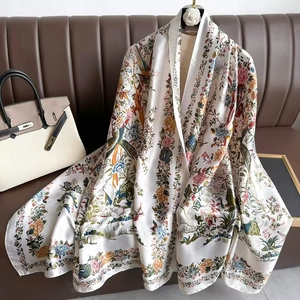 Elegant white long silk scarf with floral pattern draped over a leather sofa background