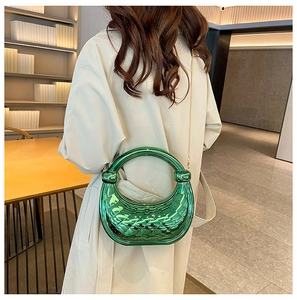 Close-up of green woven texture acrylic handbag with round handle and gold chain