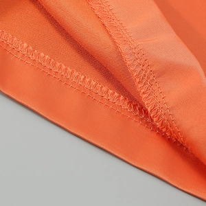 Detail view of orange twill fabric with professional overlock stitching and high-quality texture