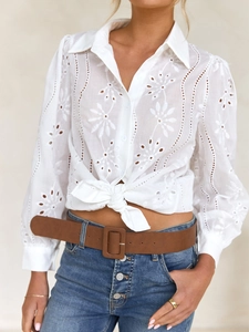 Close-up of white hollow embroidered pattern and button detail on a cotton cardigan