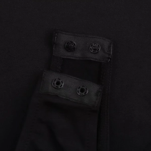 Detailed macro view of the snap-button closure on black long sleeve bodysuit