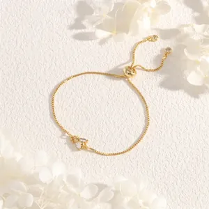 Detail of adjustable gold bee bracelet with zircon wings on a white textured background
