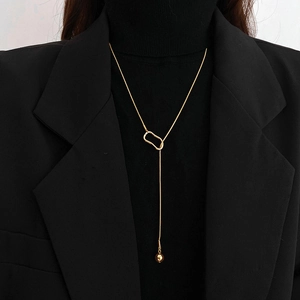 Elegant gold Y-shaped sweater necklace with geometric ring and bead on black sweater