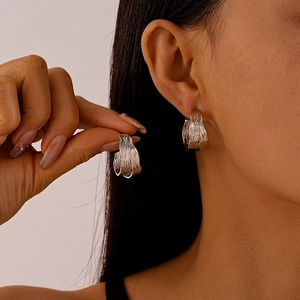 Silver wide hoop earrings with metallic crinkle texture on a female model