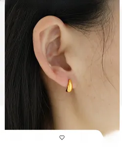 Close-up of minimalist gold teardrop earrings worn by a model for a chic look