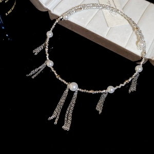 Detailed close-up of a silver pearl choker with delicate metallic tassel fringe on a display