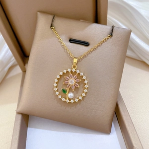 Detail of gold flower pendant necklace with pink crystals and pearl in a jewelry box