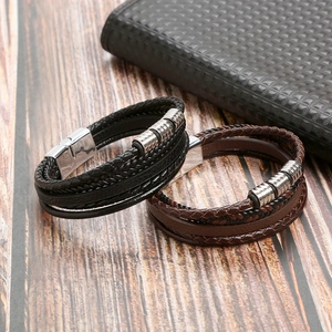 Macro detail of multi-layer black and brown leather braided bracelets with metal clasps