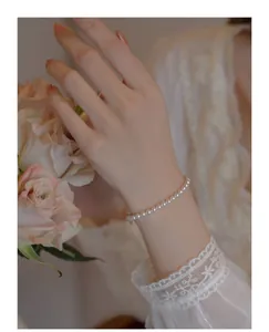 Close-up of elegant 14k gold pearl bracelet with round beads on a model's wrist