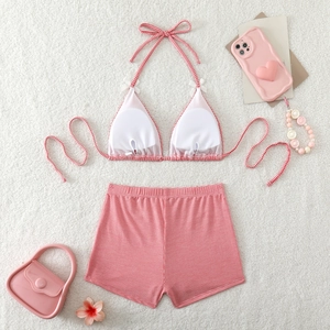 Detailed flat lay of pink checkered bikini set with white bows on plush white background