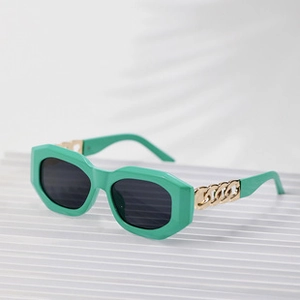 Detail view of mint green round sunglasses with golden chain metal temples on white background