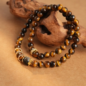 Macro detail of tiger eye stone beads and gold-plated alloy spacers on a wooden branch
