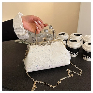 Detail of white lace evening bag featuring floral embroidery and gold metal handle